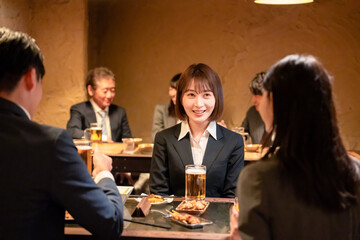 居酒屋で先輩社員とお酒を飲む新入社員