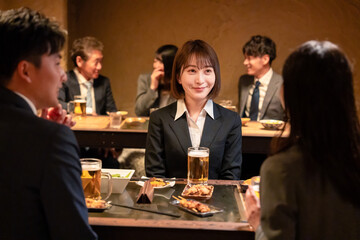 居酒屋で先輩社員とお酒を飲む新入社員