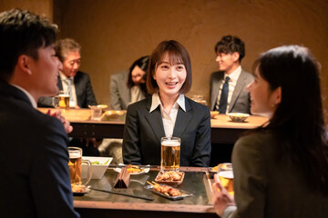 居酒屋で先輩社員とお酒を飲む新入社員