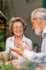 close up home happy old age an elderly couple pleasant memories leisure in old age a couple sitting at the table drinking tea discussing the news caring in old age pouring tea into cups