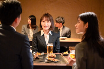 居酒屋で先輩社員とお酒を飲む新入社員
