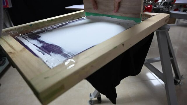 Flood and press process for screen printing a black t-shirt with white ink.