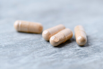 Reishi capsules. Concept for a healthy dietary supplementation. Wooden background. Soft focus. Close up.	