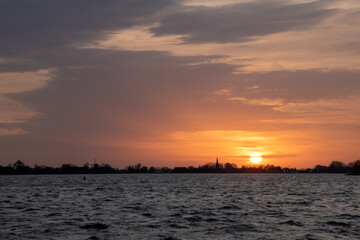 Sunset at Langweerder Wielen (Frisian: Langwarder Wielen), Frisian Lake in the Netherlands. View of the church tower of Langweer. 