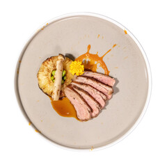 A beautifully plated dish featuring sliced meat, garnished with a grilled fruit, vibrant sauce, and edible flowers.