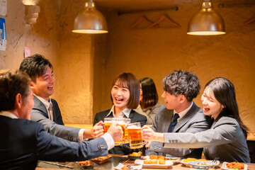 居酒屋で盛大に乾杯をするビジネスパーソン