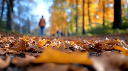 A tranquil walking path is lined with brilliant golden leaves during autumn, while blurred silhouettes in the distance create a sense of movement and a peaceful journey.