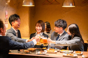 居酒屋で盛大に乾杯をするビジネスパーソン