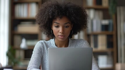A working mom reviewing documents on her laptop while sitting at a tidy desk in a minimalist office. The scene reflects professionalism without added complexity 