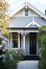 Obraz premium Charming Victorian Style House Surrounded by Lush Greenery Featuring Ornate Trim, Inviting Doorway, and Picturesque Flower Beds in a Serene Neighborhood Setting