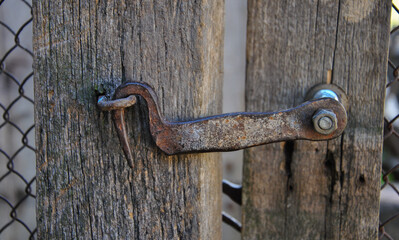 old rusty metal hook latch on a wooden fence close-up. latch on an old gate