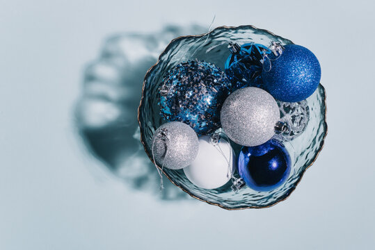 Shiny Christmas balls of blue, silver and white lie in a plate. Christmas greeting background, greeting card.