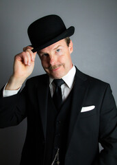 Gentleman in Suit Politely Doffing Bowler Hat in Polite Greeting. Vintage Style and Classic Manners of Proper English Gentleman.