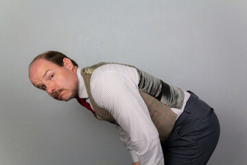 Vintage Gentleman in Tweed Waistcoat Bending Over with Curious Expression.