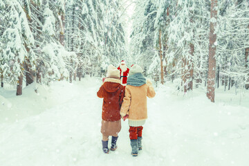 Santa Claus with a bag of gifts and children in a snowy forest. © lizavetta