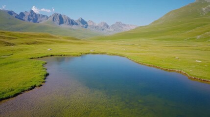 Obraz premium A serene landscape featuring a calm lake surrounded by lush green fields and majestic mountains under a clear blue sky.