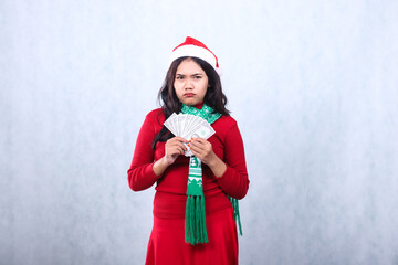 expression of young female wearing christmas sweater, santa hat and scarf, pouting forward both...