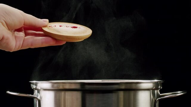 Professional chef adds paprika fragrant dry peppers to a pot of boiling food. Restaurant kitchen cooking, colorful spices, dropping spices.