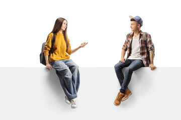 Teenagers sitting on a white wall and talking