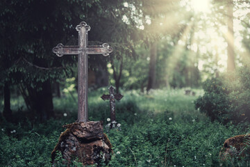 A tranquil graveyard with a weathered metal cross stands on a stone, surrounded by stunning nature and warm sunlight filtering through