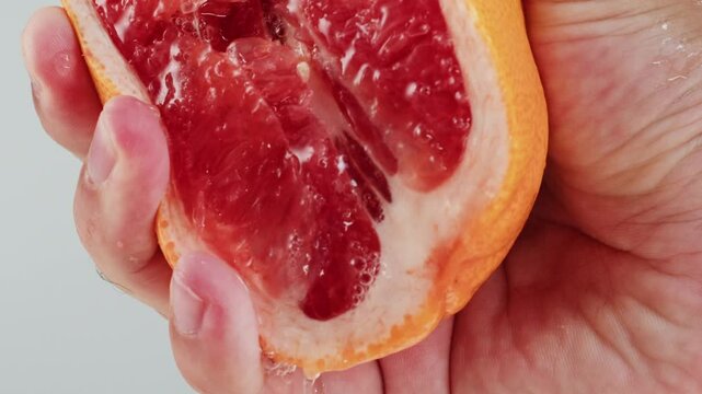 Woman pouring grapefruit juice from juicer into glass on colorful background, citrus vitamic c healthy fresh juice in cafe, morning breakfast drink.