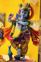 Hindu god Krishna on yellow background. Religious figurine in India.