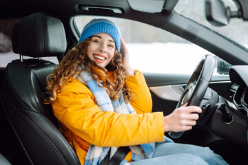 Young woman driving car on winter highway during day time.  The concept of transport, lifestyle....