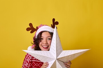 Smiling woman in Santa hat holding a large white star on yellow background