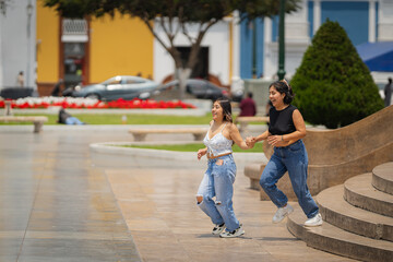 Obraz premium Two friends running and holding hands in trujillo, peru