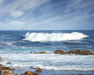 Waves, blue sky and beach with rocks, clouds and tropical holiday environment for travel getaway in nature. Water, splash and ocean horizon with natural coastline for island vacation in Australia