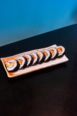Kimbap on white plate and radish,Gimbap is Korean seaweed rice roll filled with a variety of delicious fillings, egg, carrot, ham, tuna,gochujang sauce,served with kimchi, The street food of Korea..