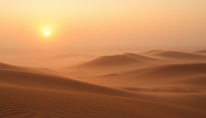 Misty desert sunrise with soft orange light illuminating sand dunes.