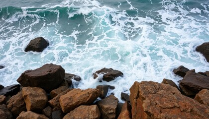 Ocean waves crashing against dark brown rocks.