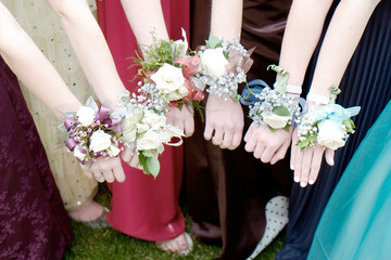 Girls Holding Arms Out with Corsage Flowers for Prom