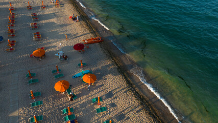 Aerial view of umbrellas and people on vacation on a sandy beach at sunset. Vacation on the sea.