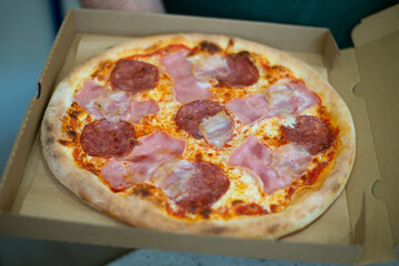 Pepperoni pizza in box with spicy salami sausage, mozzarella cheese, tomato sauce, just delivered,, black table background, top view