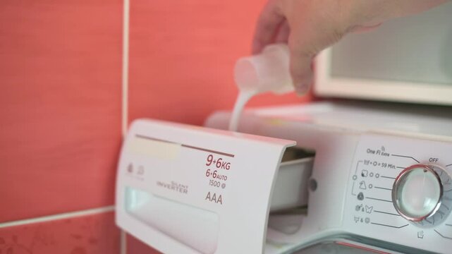 close-up of a hand pouring liquid detergent into a washing machine dispenser, preparing for a laundry wash in a home environment. washing machine pouring liquid detergent washing machine