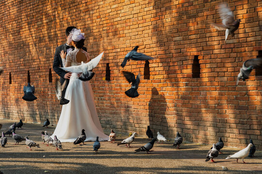 Bride and groom doing prewedding photography near old brick wall