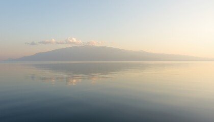 Obraz premium Serene sunrise over calm lake with mountain reflection.