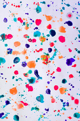 Drops of paints of different colors, on a white sheet of paper, artist's studio. Background for your creative design or addition to illustrations.