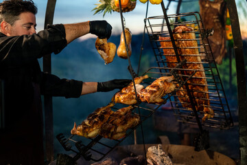 Chefs cooking BBQ and vegetables over open fire in an outdoors setting