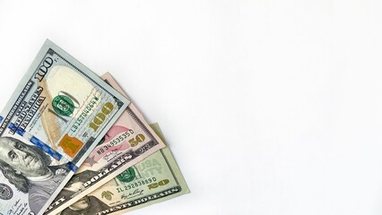 Close-up of US dollar bills including 20, 50, and 100 denominations, arranged neatly on a clean white background with ample copy space. Ideal for financial themes, investment ads, or banking promotion