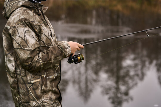 Wędkarz łowiący ryby trzymający  w rękach wędkę z kołowrotkiem