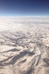 Aerial View of Snow-Capped Mountains and Clouds Stretching Across the Horizon