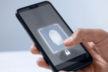 Man unlocking smartphone with fingerprint scanner on blurred background, closeup