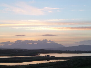 Sunset sky over the Cuillin mountains, Skye, Scotland, with Pool Roag and single silhouetted cottage in the foreground