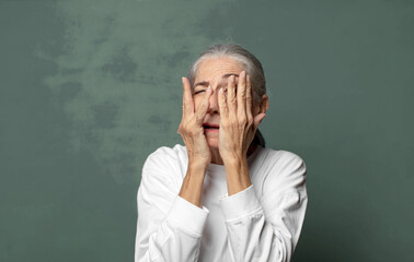  covering face with hands, peeking between fingers with surprised expression and looking to the side