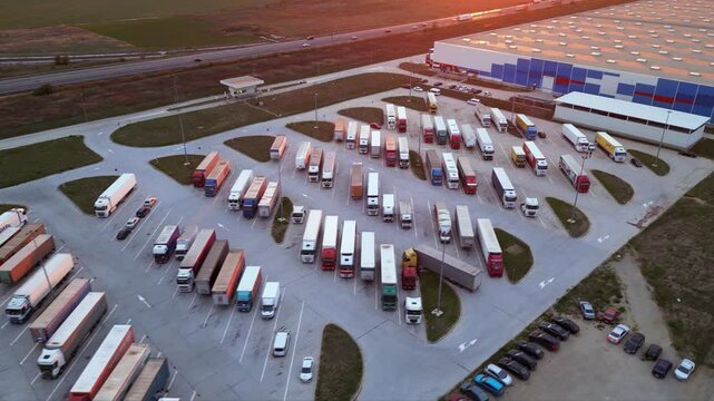 Drone shot of truck parking in Europe seen from above. Aerial footage of rows of vehicles parked for rest at a service station. Neatly placed trucks arranged at a truck stop seen from a helicopter.
