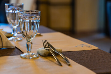 A close-up shot of a table setting in Moscow, Russia, featuring two glasses, a fork and knife, and a brown tablecloth.