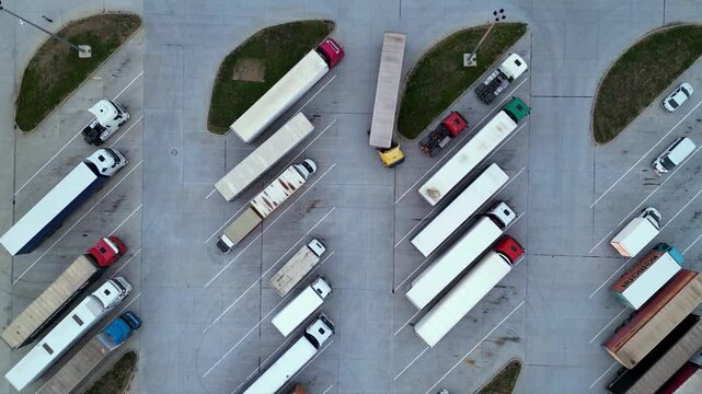 Drone shot of truck parking in Europe seen from above. Aerial footage of rows of vehicles parked for rest at a service station. Neatly placed trucks arranged at a truck stop seen from a helicopter.
